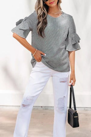 Gingham ruffled sleeve shirt in black and white polyester, styled with white ripped jeans.
