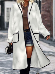 White teddy coat with black contrast trim, open front, and pocket details.