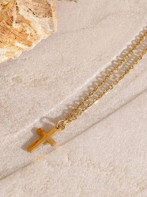 Gold layered pendant necklace with a cross charm and adjustable length.