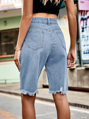 Light blue denim cutoff shorts with distressed hem and knee detail