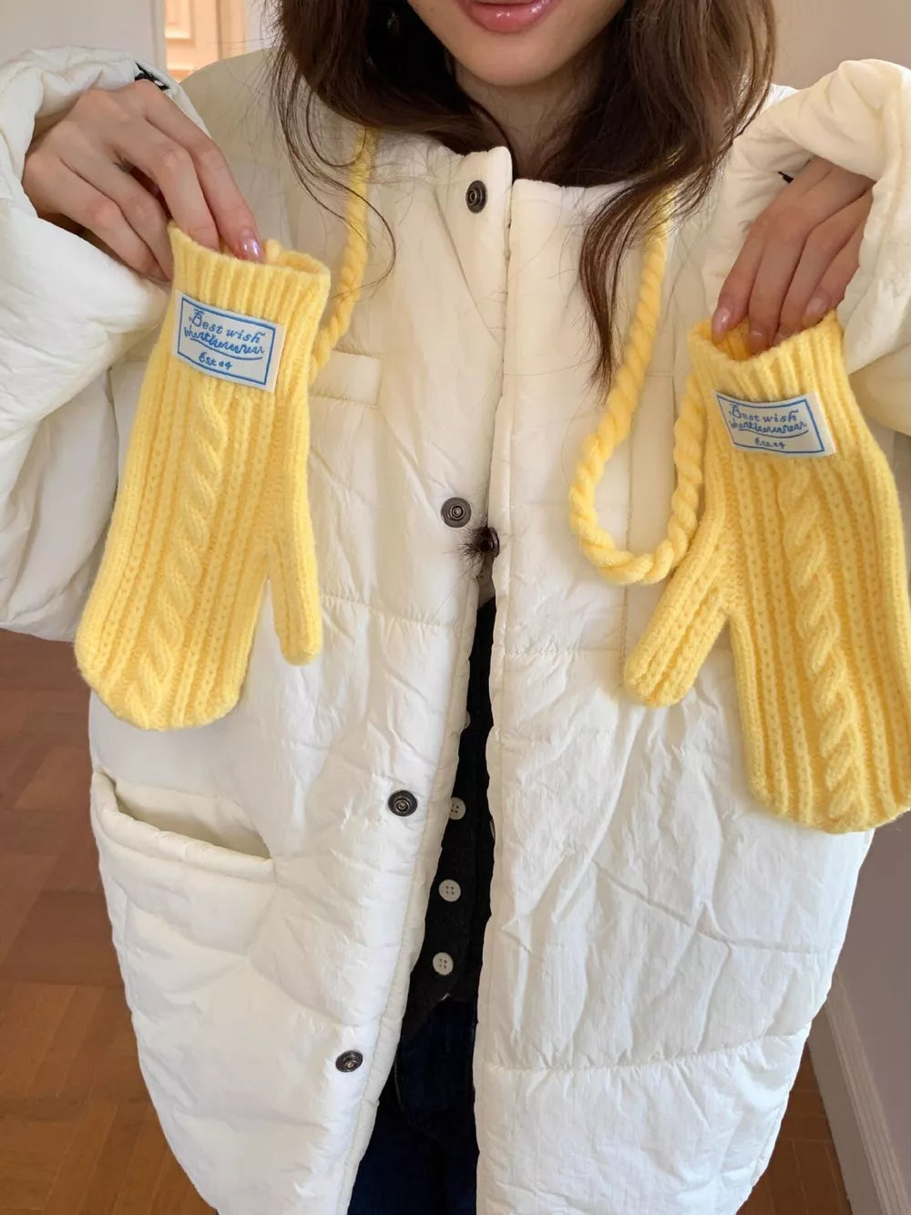 Yellow cable knit acrylic gloves with braided detail and a blue tag.