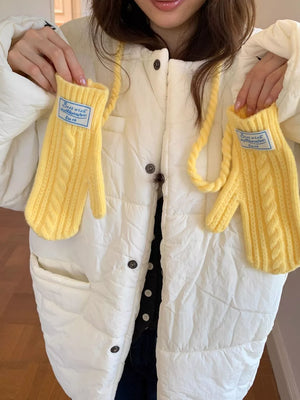 Yellow cable knit acrylic gloves with braided detail and a blue tag.