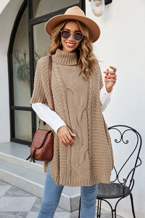 Camel cable knit turtleneck poncho with side slit and short sleeves, styled with a white shirt and jeans.