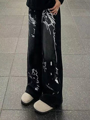 Men's black wide-leg jeans with white graffiti print and light tan shoes.