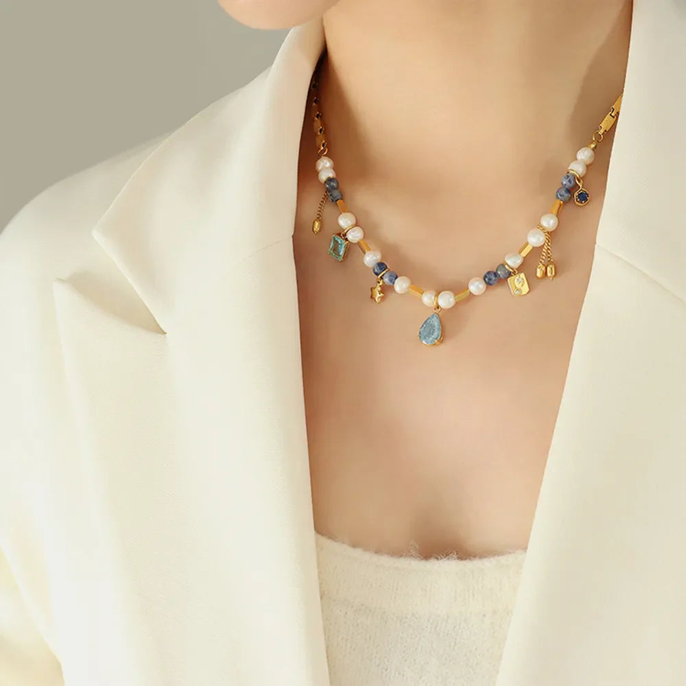 Gold celestial charm necklace with pearls, blue beads, and dangling charms.