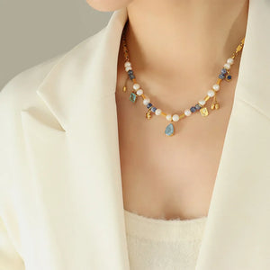 Gold celestial charm necklace with pearls, blue beads, and dangling charms.