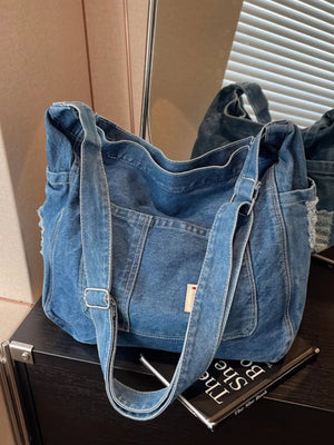 Slouchy blue denim crossbody bag with contrast stitching and adjustable strap.