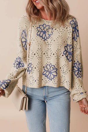 Beige eyelet knit pullover with blue floral embroidery and long sleeves.