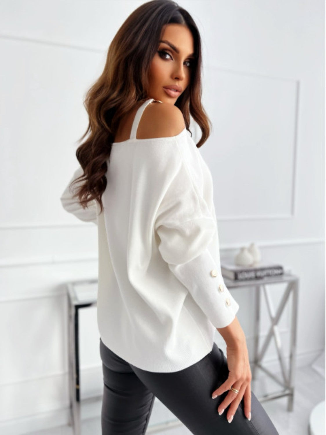 White off-shoulder knit top with buckle detail on strap and button detail on sleeves.