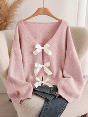 Pink V-neck cardigan with balloon sleeves and three white bow-knot details.