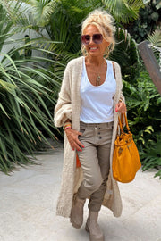 Long knit cardigan in beige with open front and balloon sleeves, worn over a white tank top.