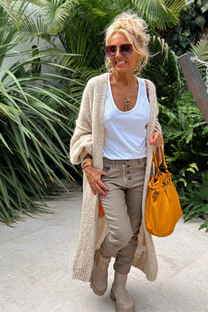 Long knit cardigan in beige with open front and balloon sleeves, worn over a white tank top.