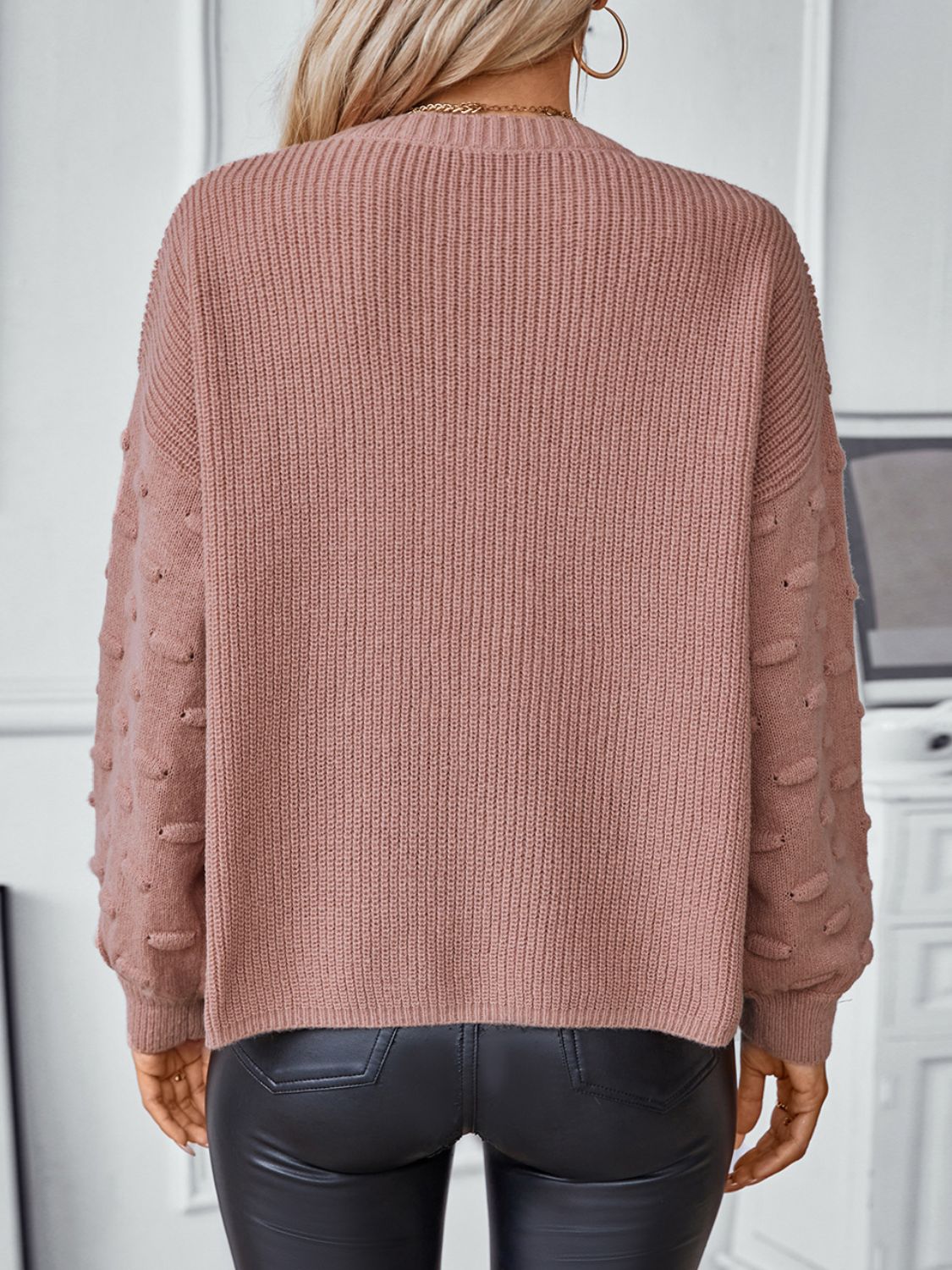 Dusty pink knit sweater with textured sleeve details and a ribbed crew neck.