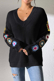 Black knit sweater with colorful granny square sleeve details, V-neck, and ribbed cuffs.