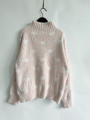 Blush pink acrylic turtleneck sweater with allover white heart motif and textured knit.