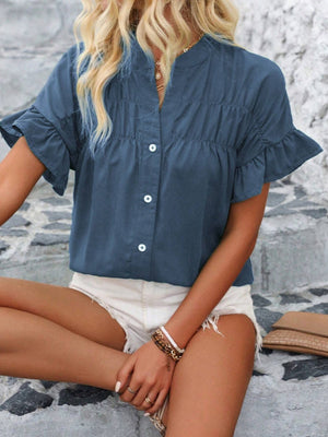 Dusty blue button-up blouse with gathered yoke and ruffle sleeves.