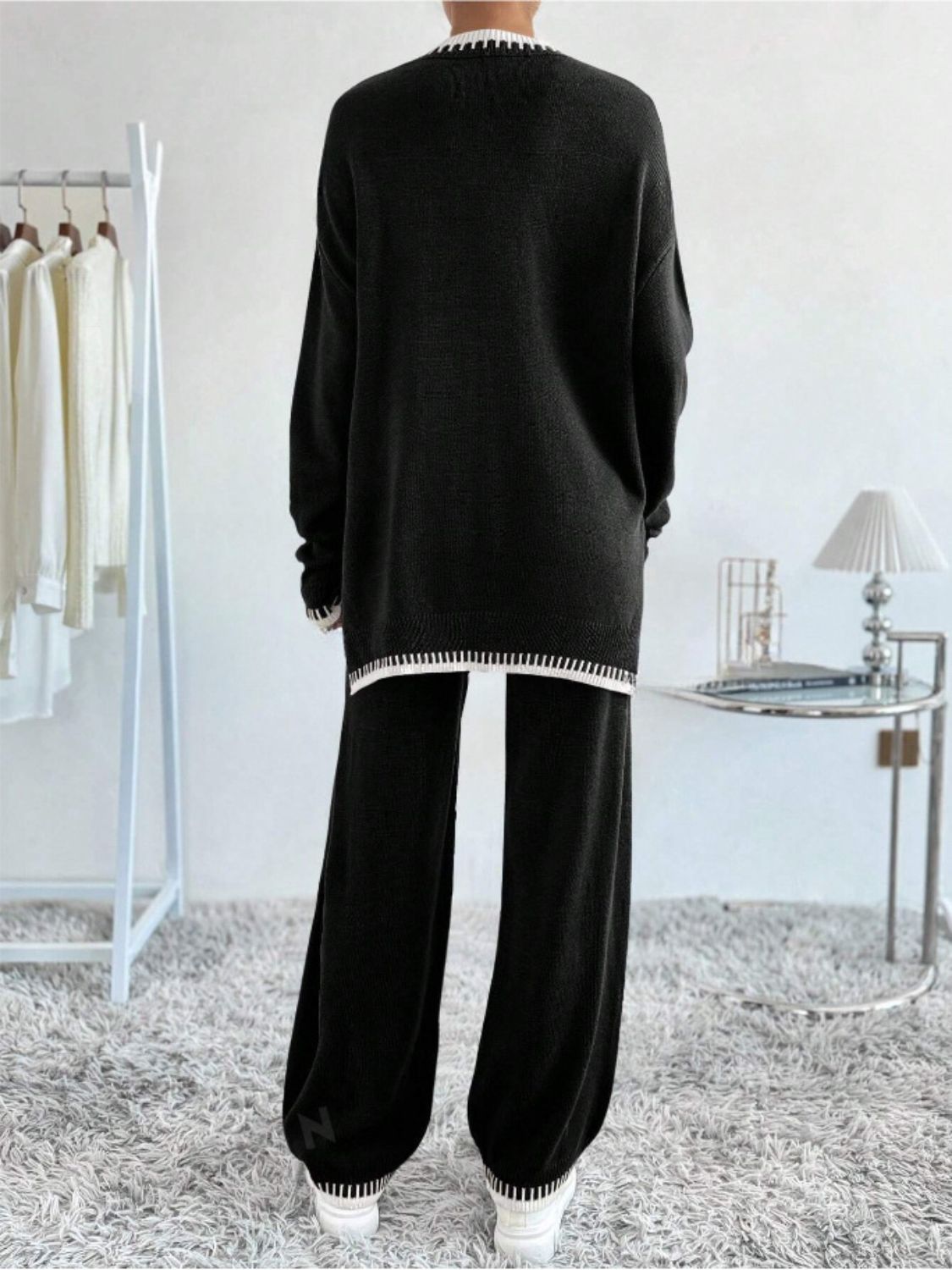 Black knit loungewear set with white striped trim and slit detail on sweater.