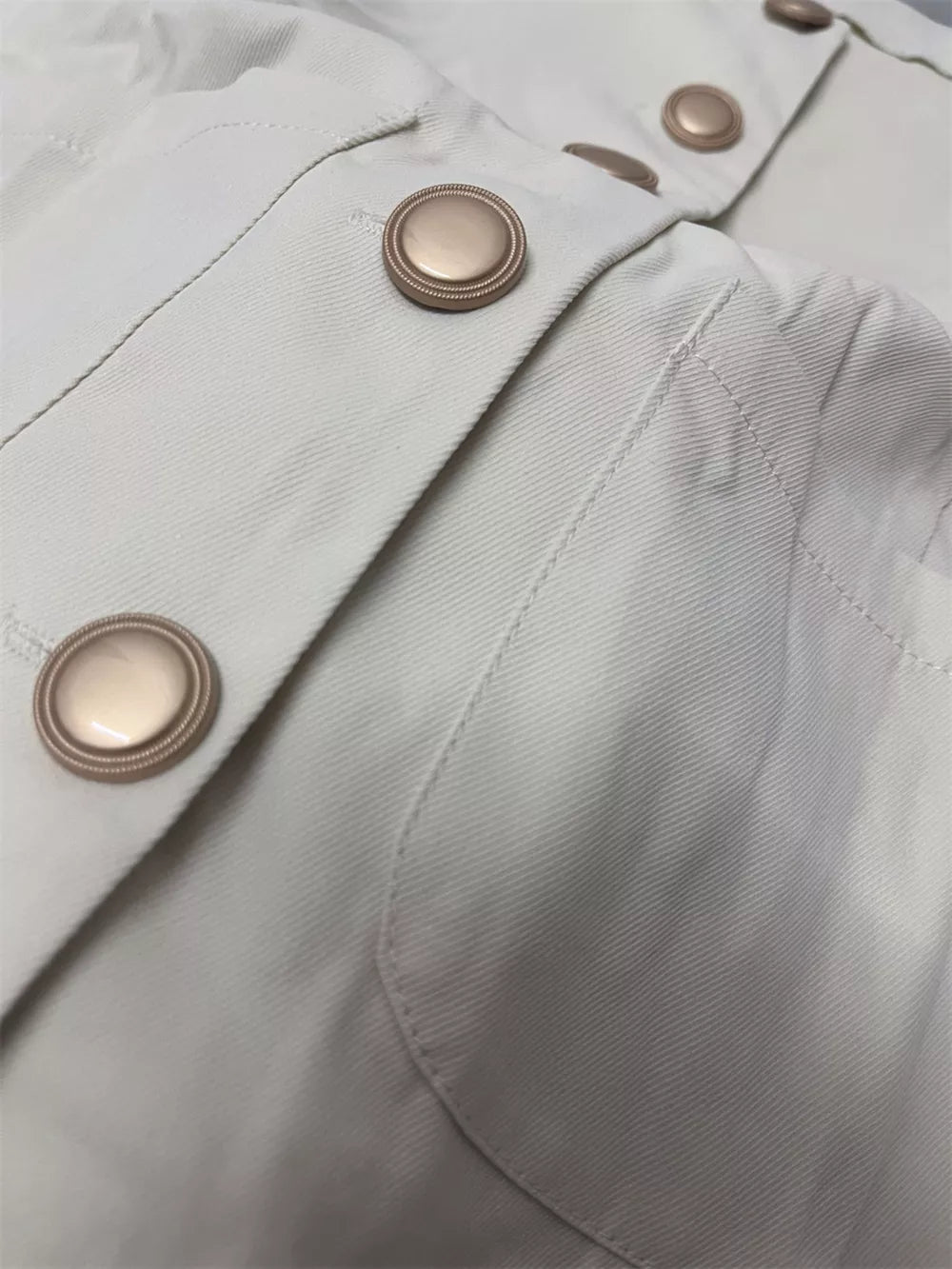 Cream cotton button-down sleeveless vest with crew neck and gold buttons.