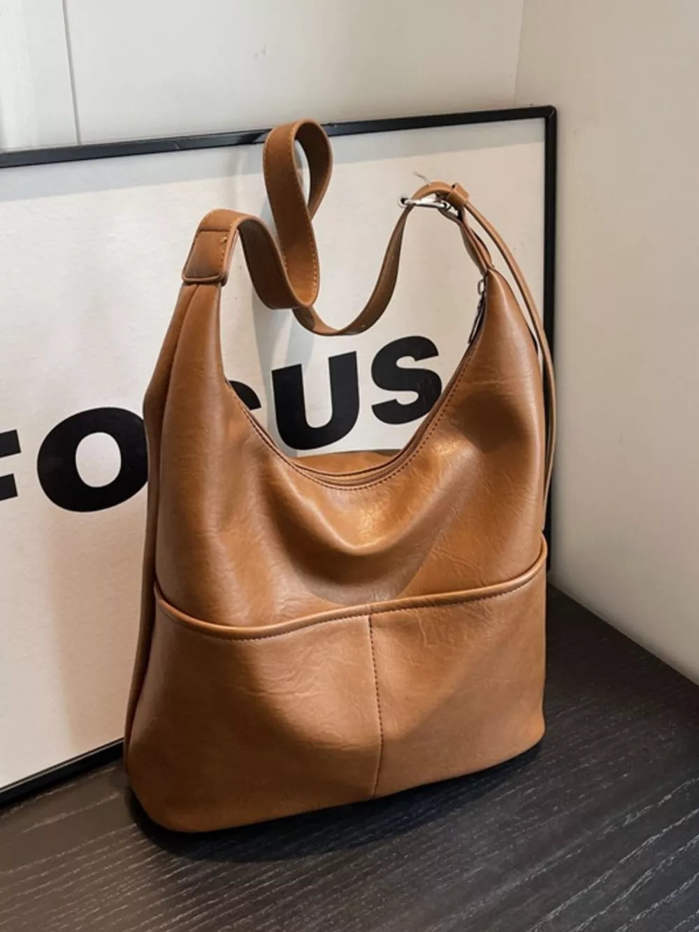 Brown leather hobo shoulder bag with adjustable strap and front pocket detail
