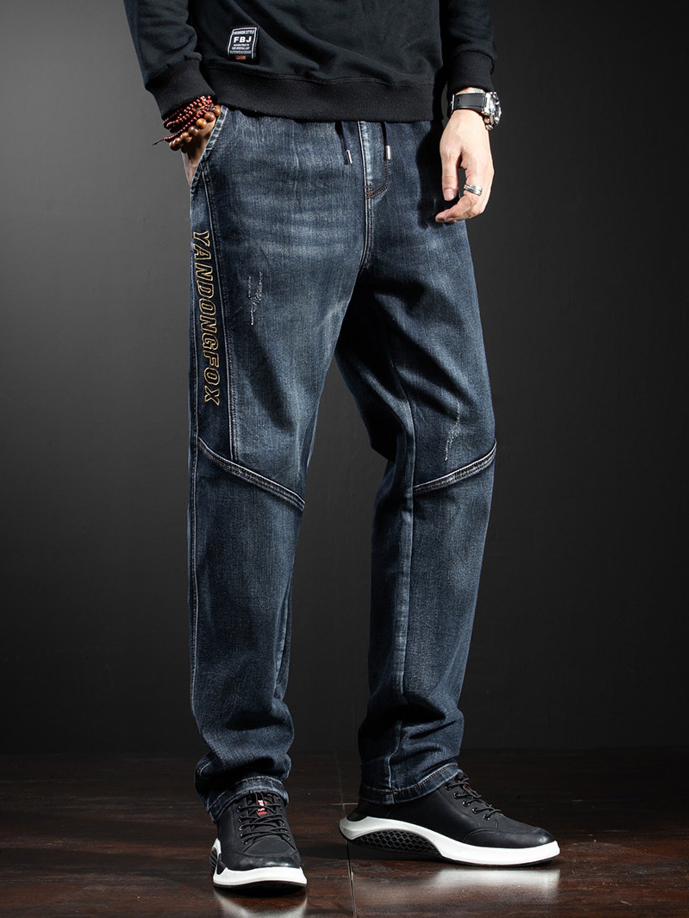 Men's dark wash loose fit drawstring jeans with distressed details and side text