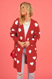 Red longline knit cardigan with white heart motif, pockets, and open front.