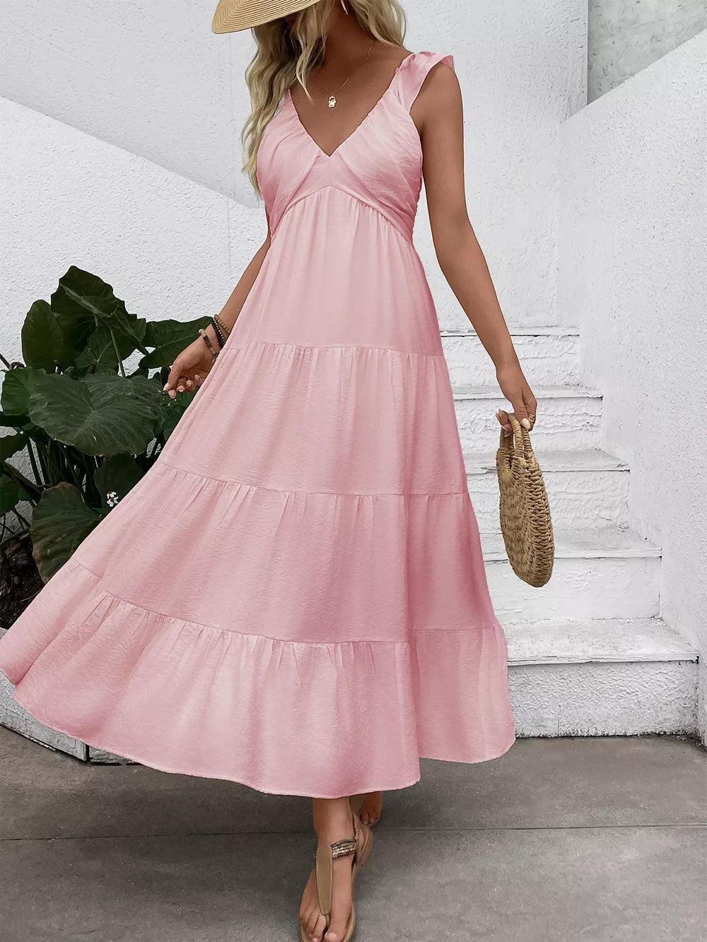 Blush pink tiered maxi dress with flutter sleeves and V-neck, flowing skirt.