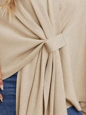 Beige knit cape top with tie-front detail and draped elegance.