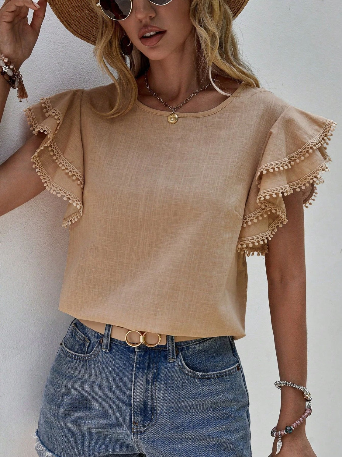 Khaki blouse with pom-pom trimmed ruffle sleeves and round neckline.