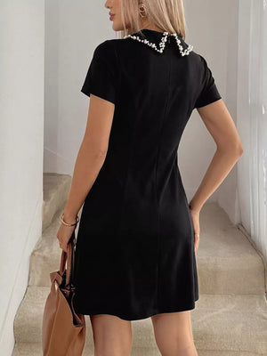 Black A-line mini dress with beaded collar and short sleeves.