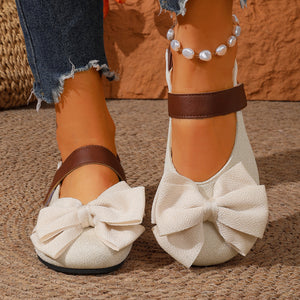 Beige textured round toe flats with large bow detail and brown strap.