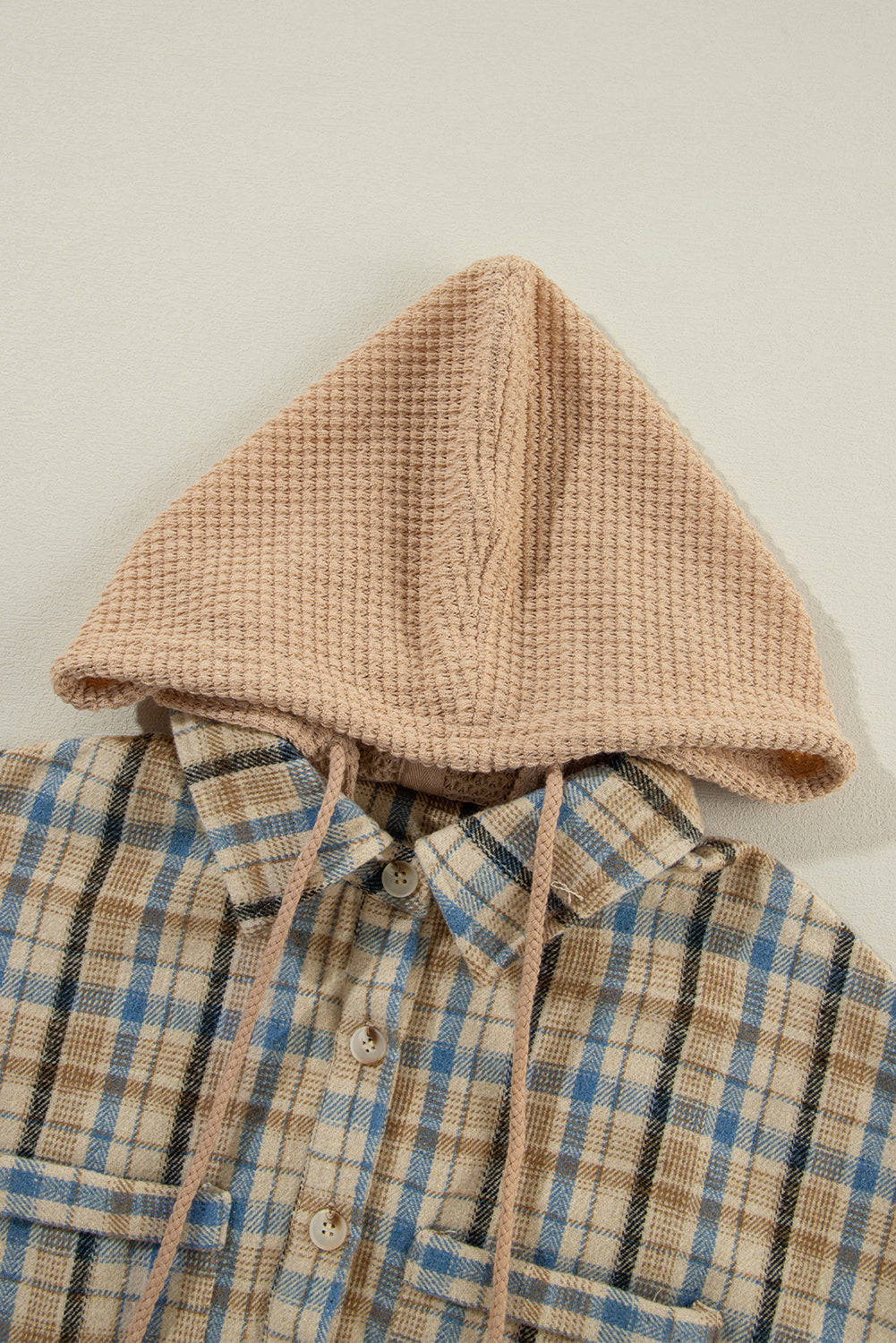 Textured plaid hooded overshirt with drawstring and raw hem detail.