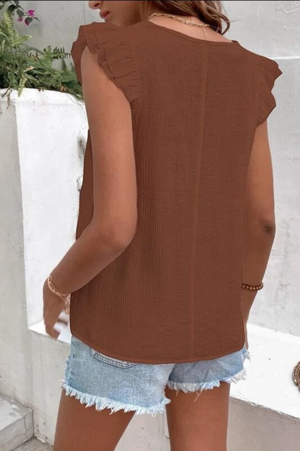 Brown flutter sleeve blouse with textured fabric and embroidered trim.