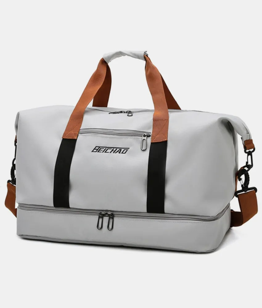 Gray dual-compartment weekender bag with contrast black and brown straps and a zippered bottom compartment.