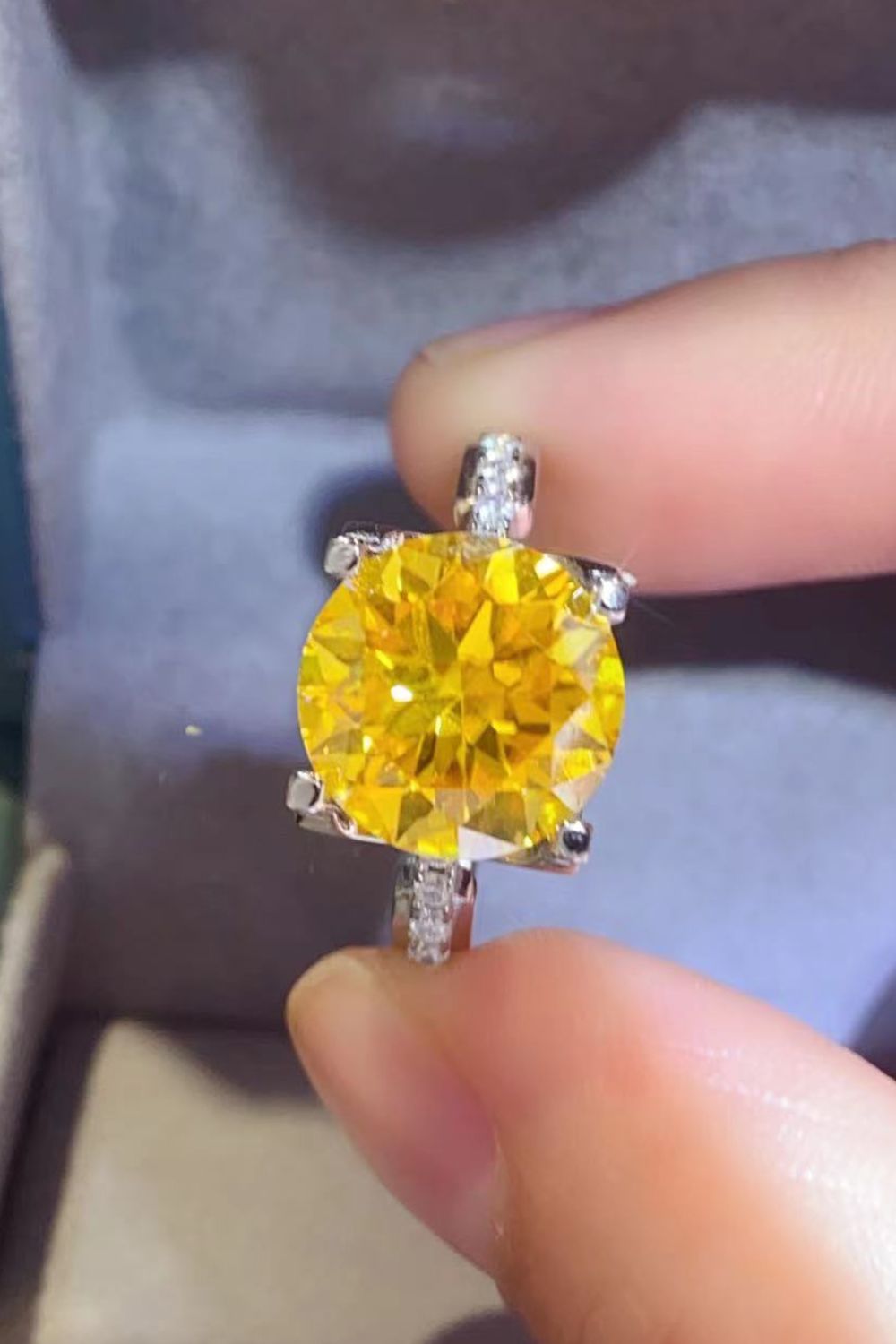 Silver solitaire ring with a bright yellow canary diamond and small accent stones.