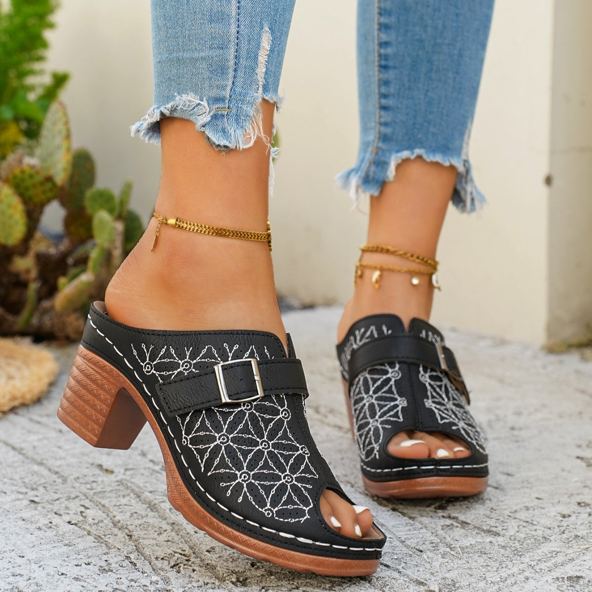 Black buckle sandals with white floral embroidery and block heel.
