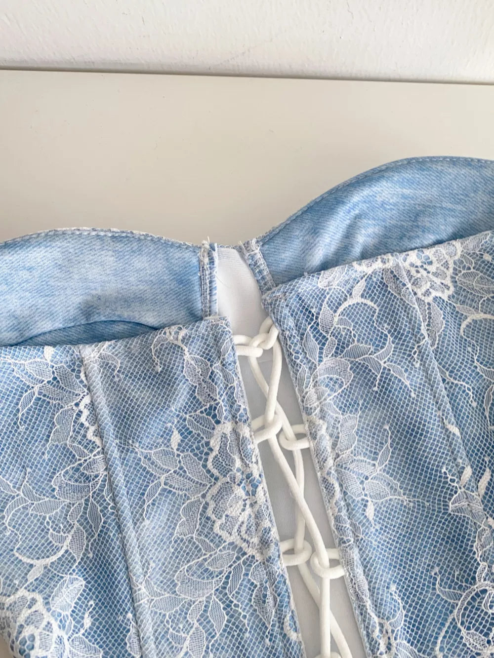 Blue lace corset top with white lace overlay and adjustable front lacing detail.