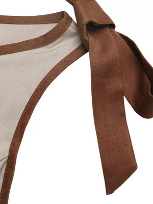 Maternity romper detail with brown trim and tie shoulder bows.