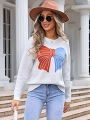Ivory knit sweater with a red and blue graphic bow on the front.