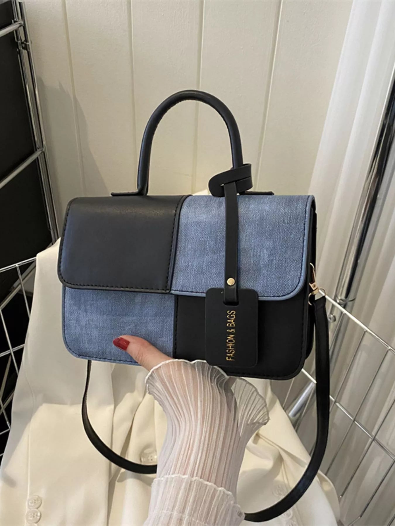 Chic two-tone black and blue PU leather crossbody handbag with top handle and tag.
