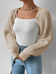 Khaki acrylic knit bolero shrug with long sleeves, styled with a white camisole and jeans.