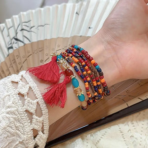 Beaded tassel stacked bracelet set with red tassels and colorful beads.