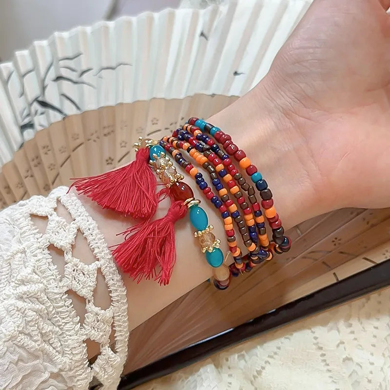 Beaded tassel stacked bracelet set with red tassels and colorful beads.