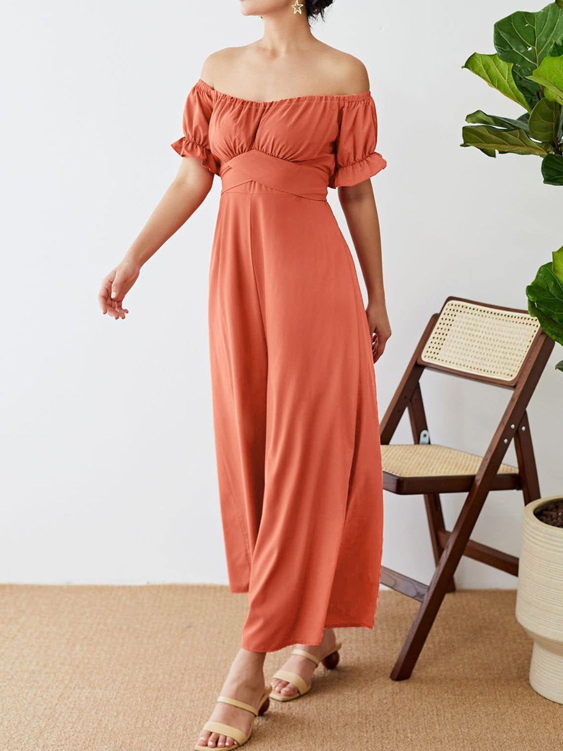 Coral off-the-shoulder jumpsuit with ruched waist and puff sleeves.