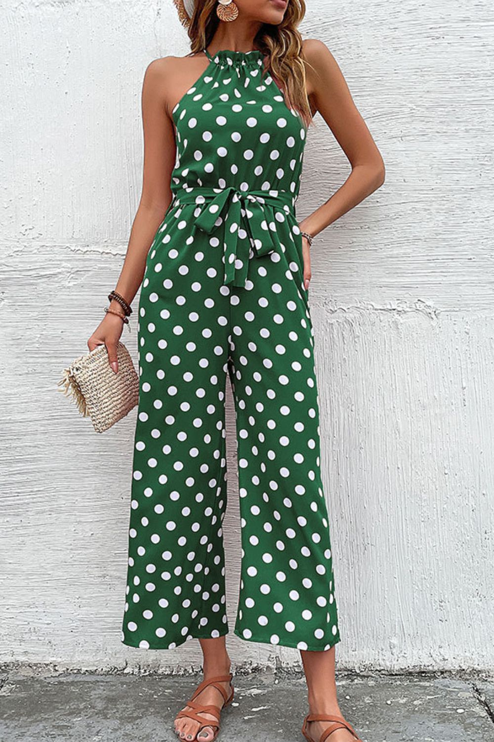 Green polka dot halter neck palazzo jumpsuit with tie waist and wide legs.