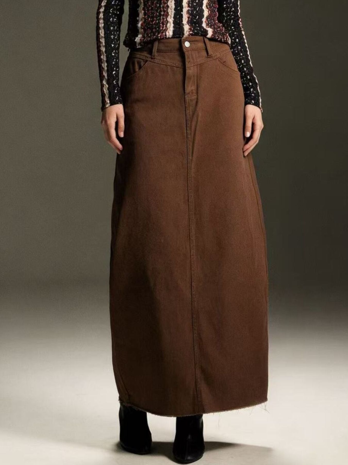 Brown denim maxi skirt with raw hem and button closure.