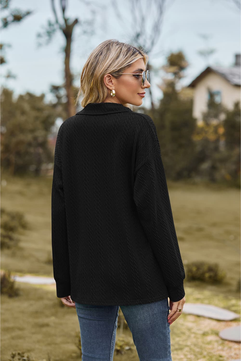 Black textured cable knit polo top with a collared neckline and long sleeves.