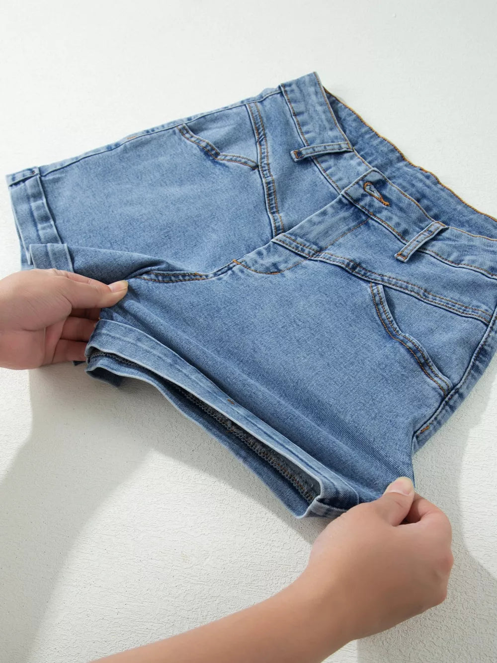 Light blue cotton denim shorts with cuffed hems and button closure.