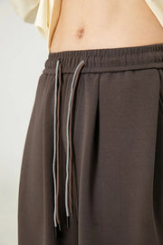 Oversized lounge trousers in coffee brown with drawstring and drape-front detail.