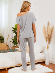 Gray loungewear set with asymmetric neckline and straight leg pants.