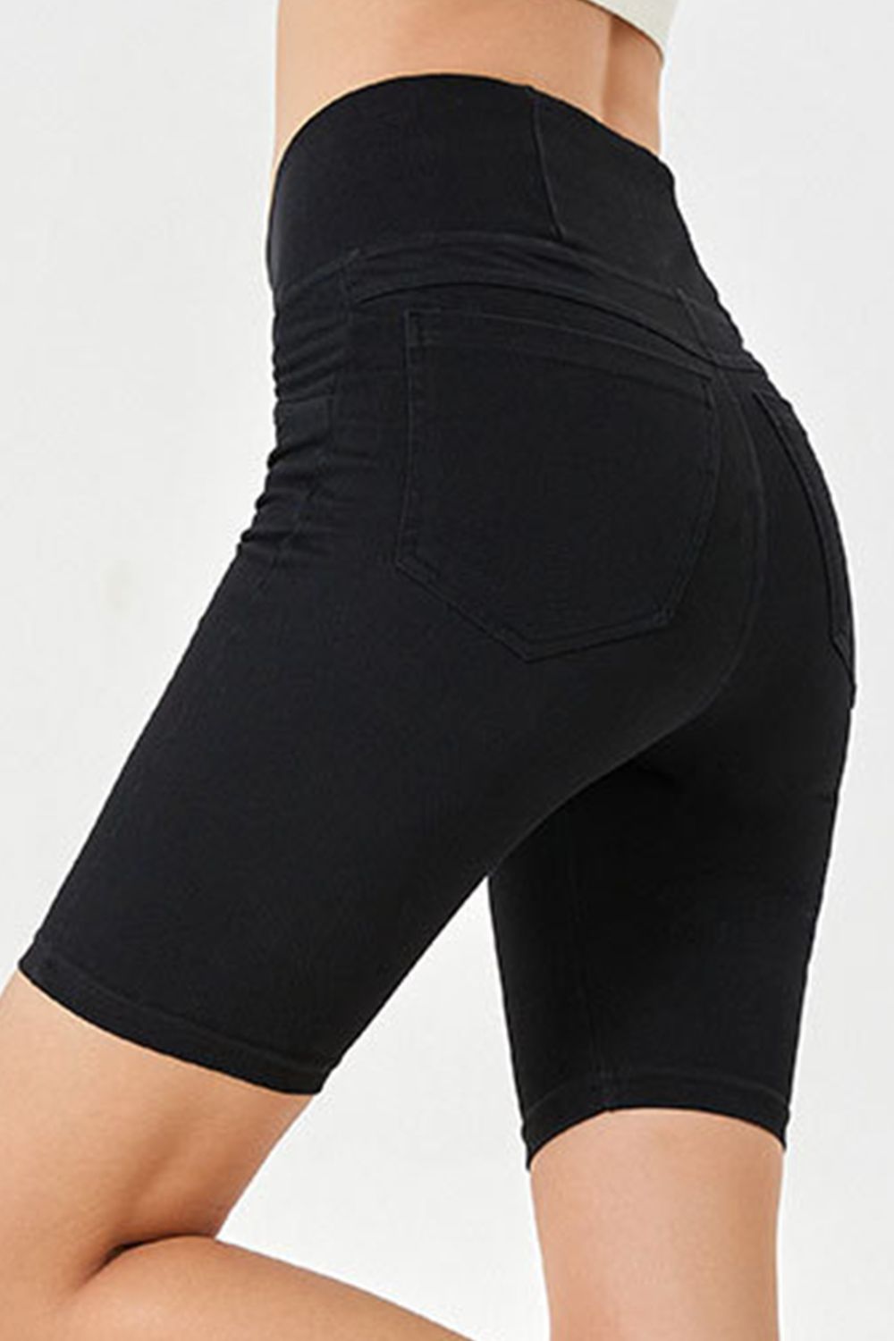 Black denim bermuda shorts with a crisscross waistband and ruched detail.